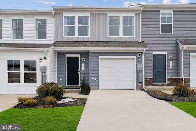 townhome / multi-family property featuring driveway, an attached garage, and roof with shingles