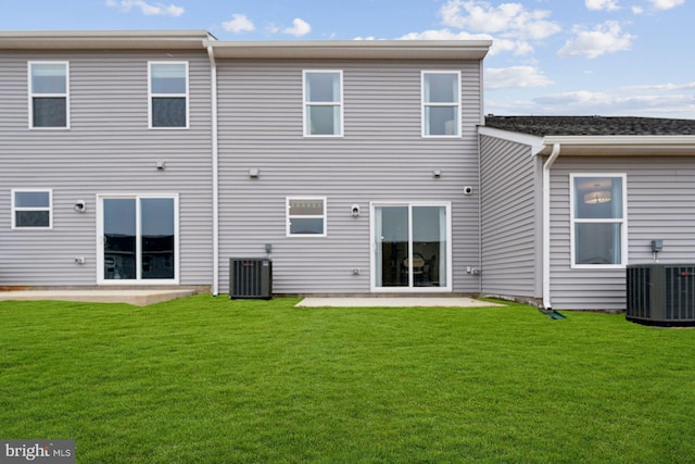 rear view of property with cooling unit, a patio, and a lawn