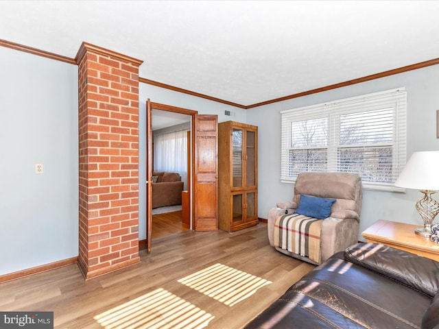 living area with light wood-type flooring, crown molding, and baseboards