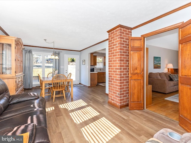 living area featuring light wood-style floors, crown molding, and an inviting chandelier