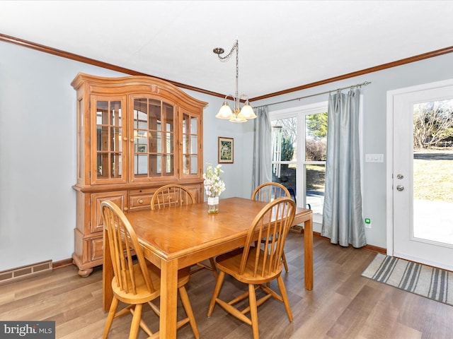 dining area featuring light wood finished floors, visible vents, an inviting chandelier, ornamental molding, and baseboards