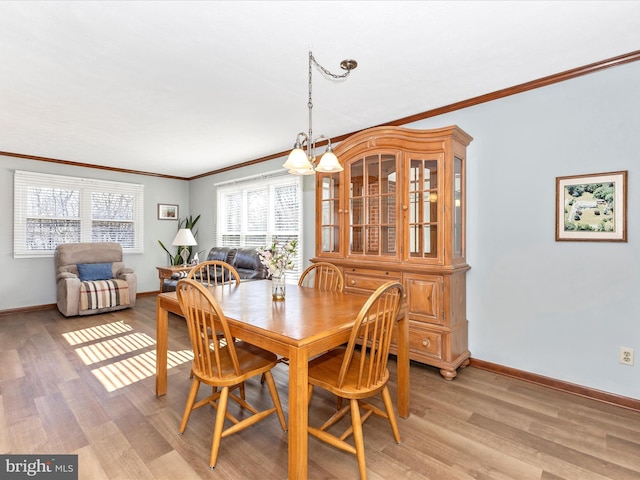 dining space with light wood-type flooring, crown molding, and baseboards