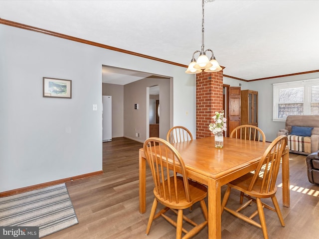 dining space with crown molding, light wood finished floors, a chandelier, and baseboards