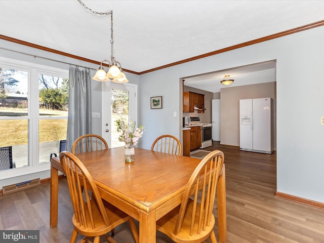 dining area with crown molding, wood finished floors, visible vents, and baseboards