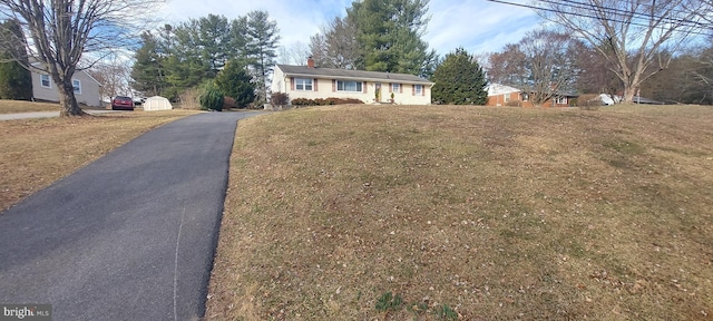 ranch-style home with aphalt driveway, a chimney, and a front lawn