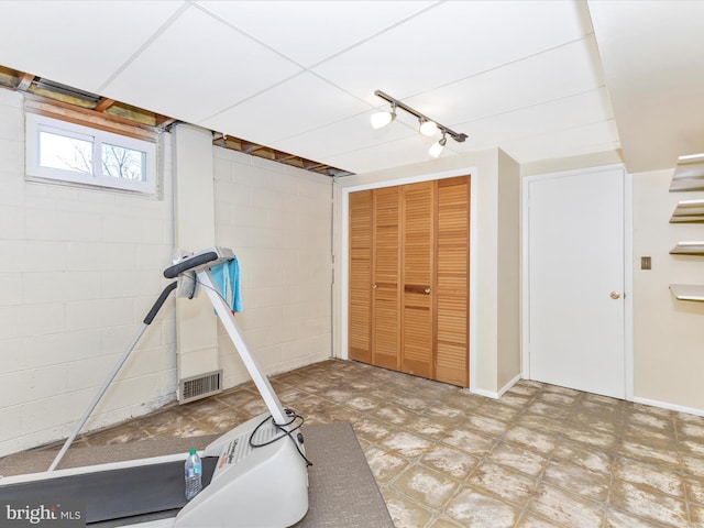 workout room featuring concrete block wall, visible vents, and tile patterned floors