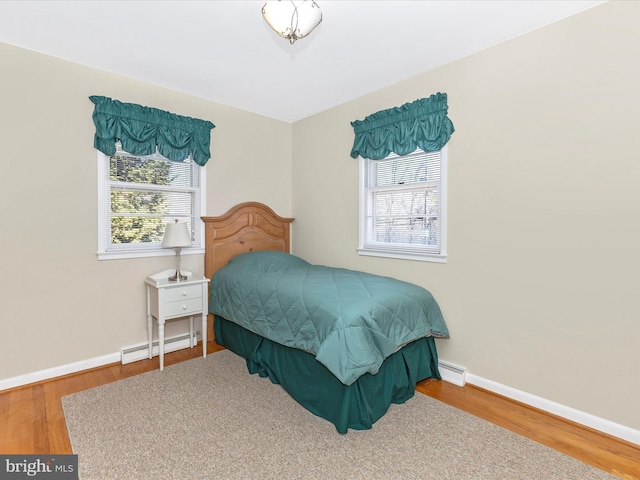 bedroom featuring a baseboard radiator, wood finished floors, and baseboards