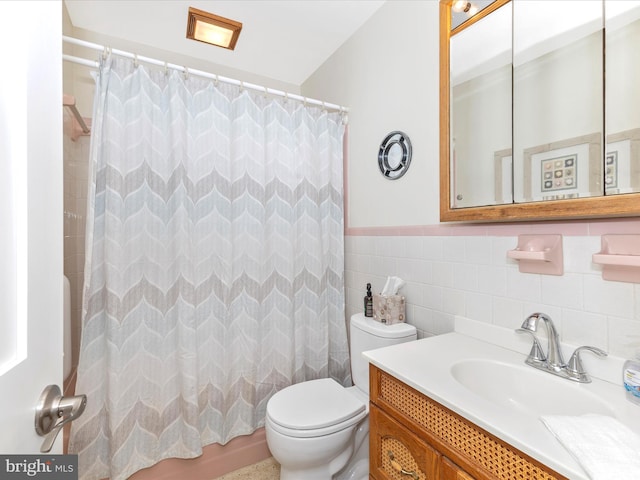 bathroom featuring toilet, a shower with shower curtain, wainscoting, and tile walls