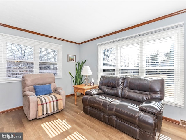 living room featuring ornamental molding, baseboards, visible vents, and light wood finished floors