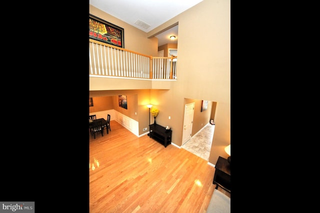 living room featuring a high ceiling, wood finished floors, and visible vents