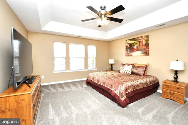 bedroom featuring visible vents, baseboards, a ceiling fan, carpet, and a tray ceiling