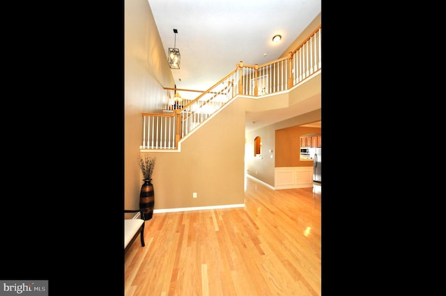 interior space featuring a towering ceiling, baseboards, and wood finished floors