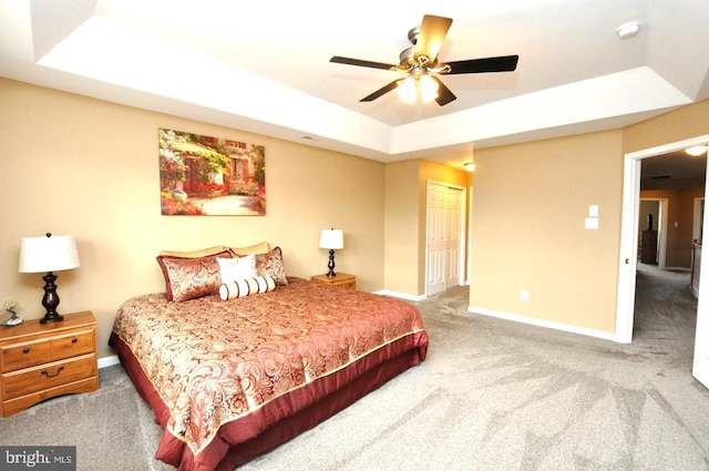 bedroom featuring a tray ceiling, a closet, carpet flooring, and baseboards