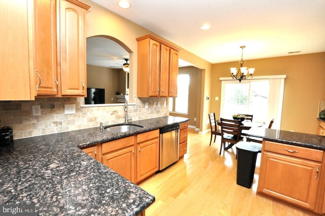 kitchen with a sink, light wood-style floors, hanging light fixtures, stainless steel dishwasher, and backsplash