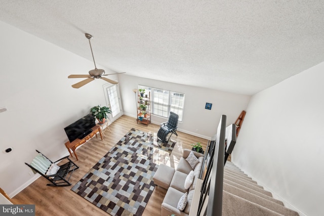 living room featuring lofted ceiling, a textured ceiling, wood finished floors, baseboards, and stairs