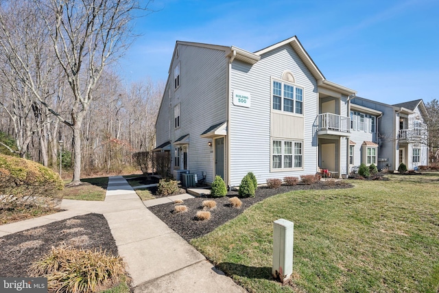 townhome / multi-family property featuring a front yard, a balcony, and central AC unit