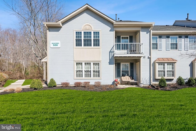 rear view of house featuring a yard and a balcony