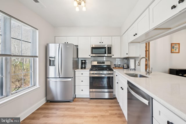 kitchen with stainless steel appliances, light countertops, a sink, and light wood-style flooring