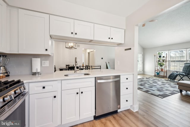 kitchen with white cabinets, appliances with stainless steel finishes, light countertops, light wood-style floors, and a sink