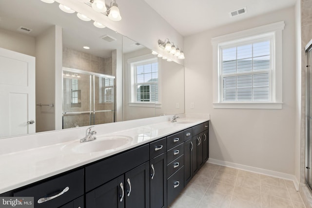 full bathroom with baseboards, double vanity, a sink, and a shower stall