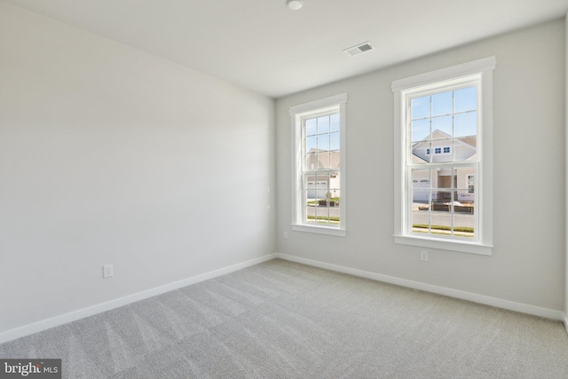 empty room featuring carpet, visible vents, and baseboards