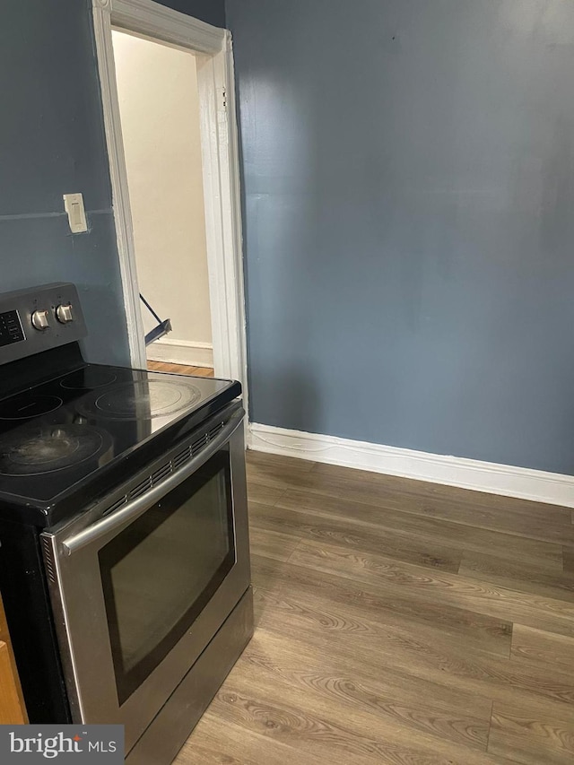 kitchen with electric range, baseboards, and wood finished floors