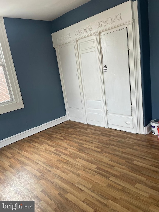 unfurnished bedroom featuring a closet, baseboards, and wood finished floors