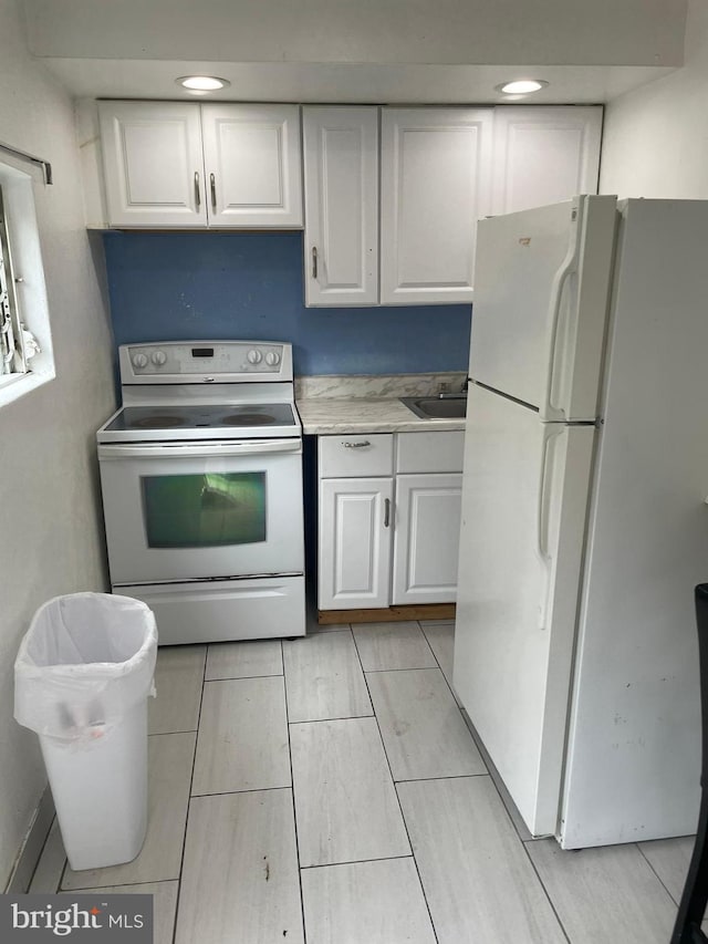 kitchen featuring light countertops, white appliances, white cabinetry, and a sink