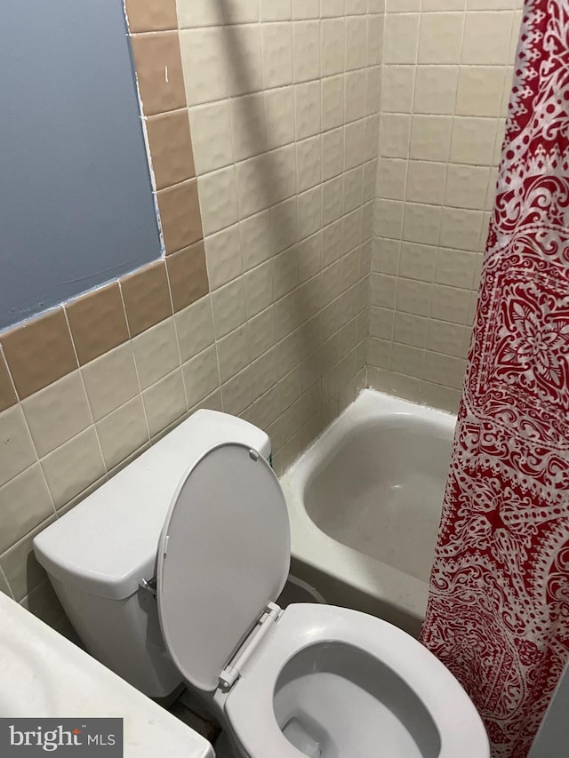 bathroom featuring toilet, a washtub, tile walls, and a shower with shower curtain