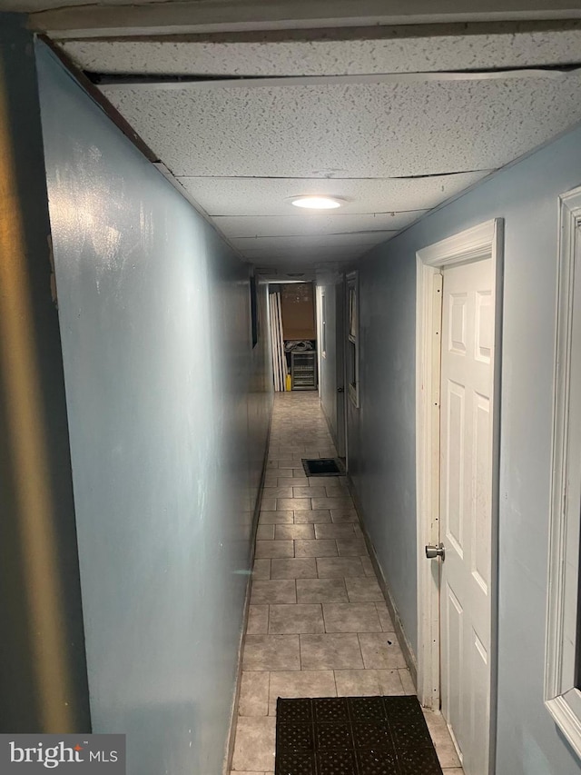 corridor featuring a paneled ceiling and baseboards