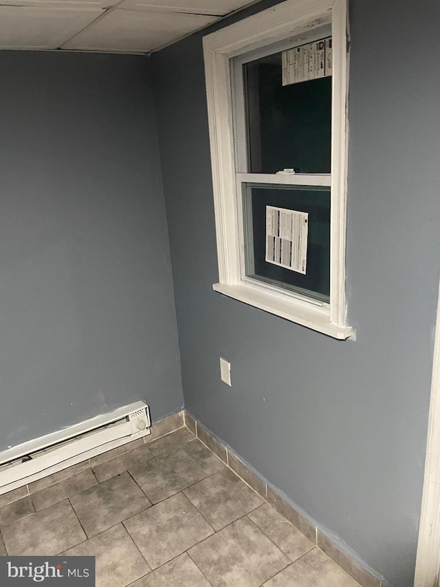 tiled spare room featuring baseboard heating, a paneled ceiling, and baseboards