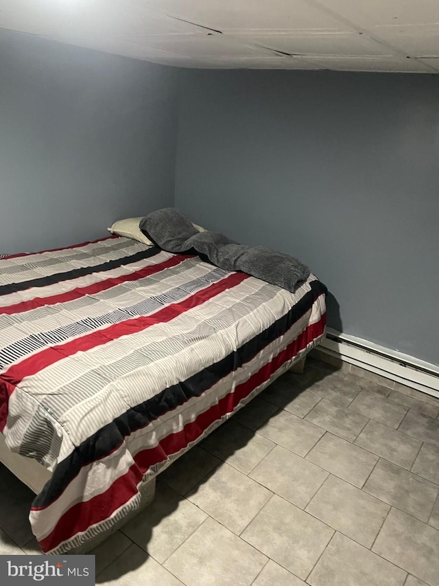 bedroom with a baseboard heating unit and tile patterned flooring