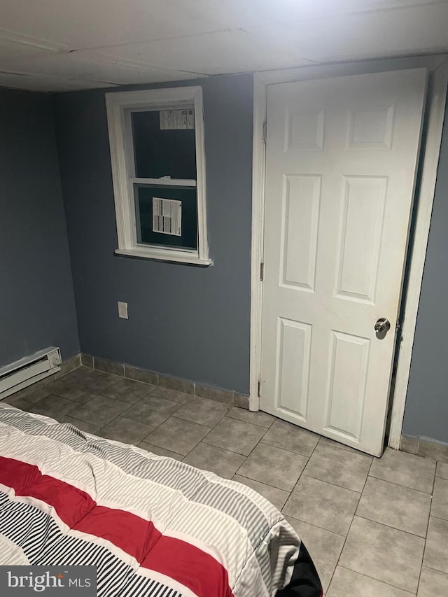 tiled bedroom with a baseboard heating unit and baseboards