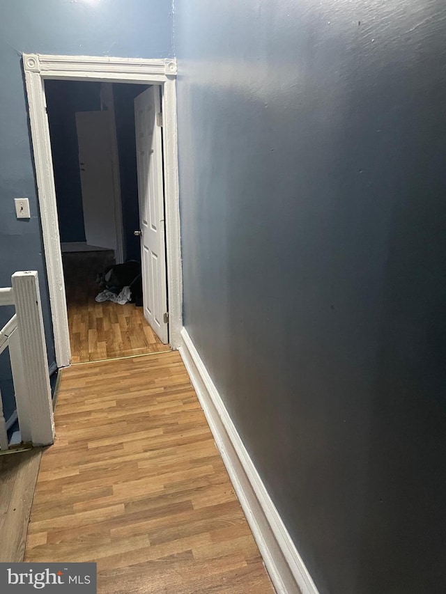 corridor with light wood-type flooring and baseboards