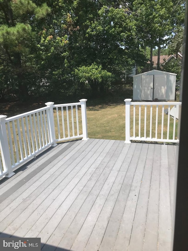 deck featuring a storage unit, a lawn, and an outdoor structure