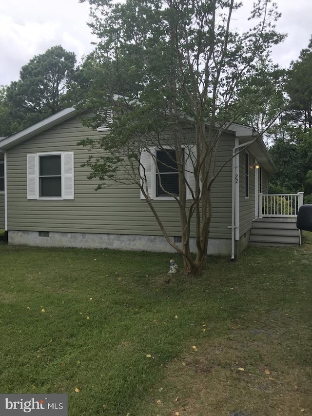 view of side of property with crawl space and a yard