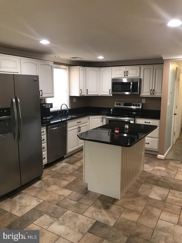 kitchen featuring appliances with stainless steel finishes, dark countertops, a sink, and white cabinets