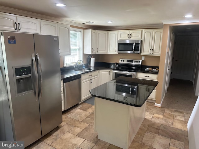 kitchen with a kitchen island, a sink, appliances with stainless steel finishes, stone finish flooring, and dark countertops