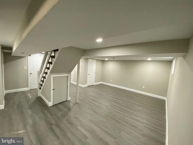 finished basement with stairway, recessed lighting, wood finished floors, and baseboards