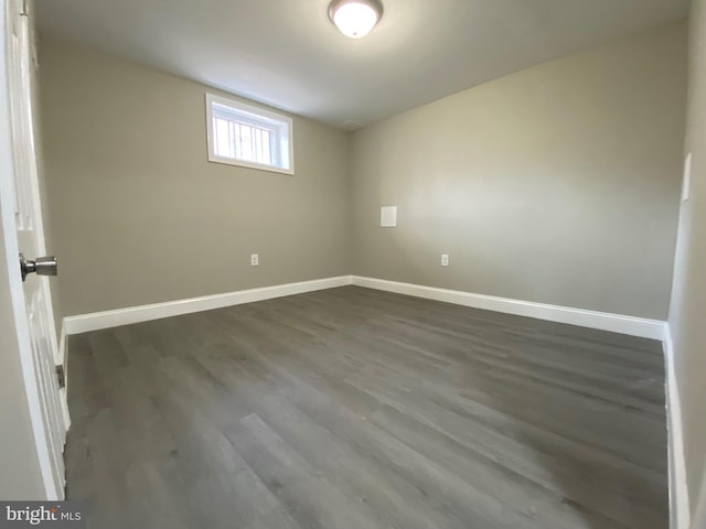 empty room with baseboards and dark wood-type flooring