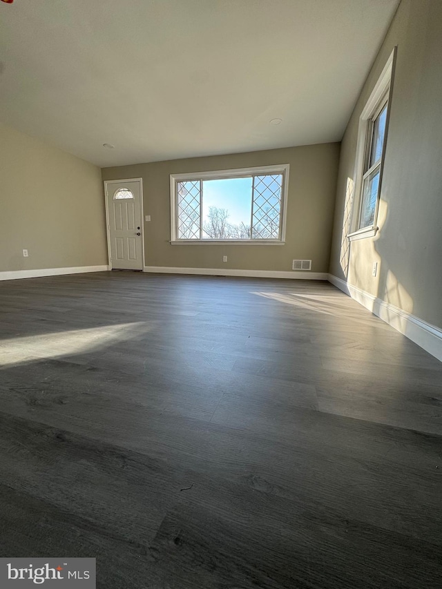 unfurnished living room featuring baseboards and dark wood-style flooring