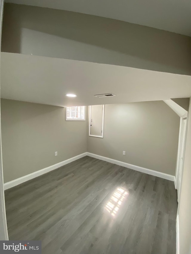 basement with dark wood-style floors, visible vents, and baseboards