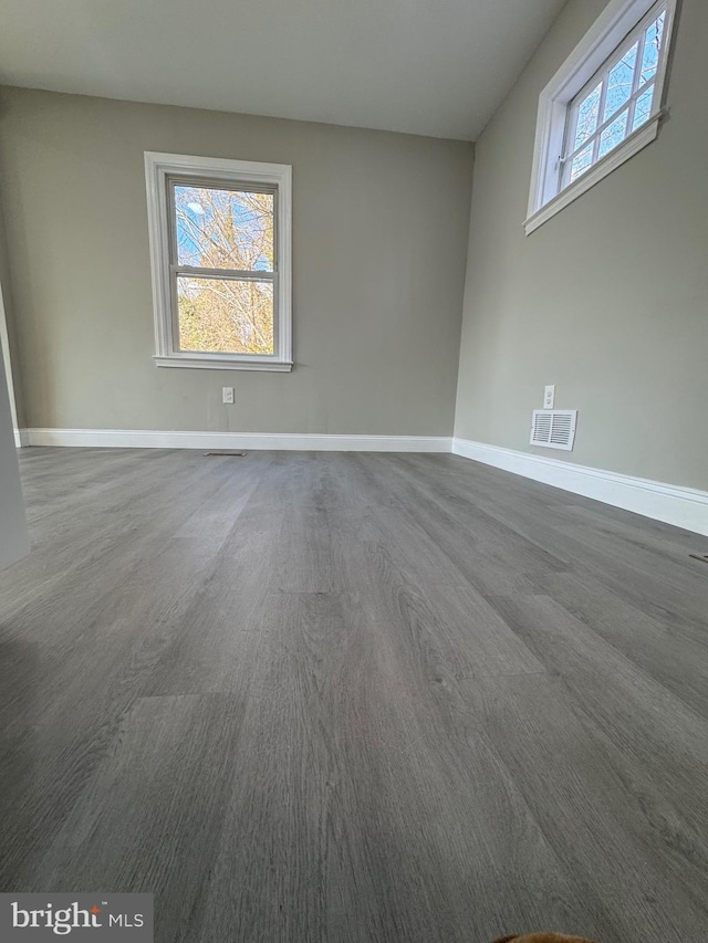 empty room featuring a wealth of natural light, visible vents, and baseboards