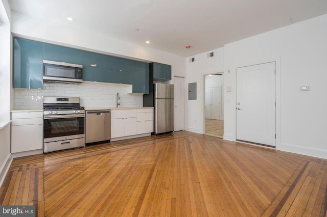 kitchen featuring light wood-type flooring, decorative backsplash, stainless steel appliances, and light countertops