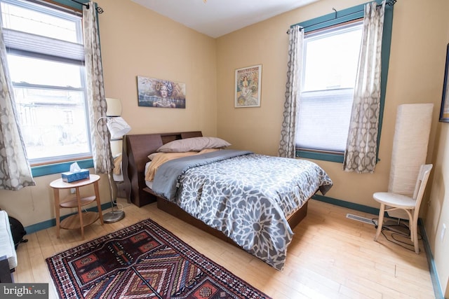 bedroom featuring multiple windows, baseboards, and wood finished floors