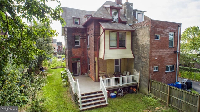 rear view of property featuring a deck, a yard, and brick siding