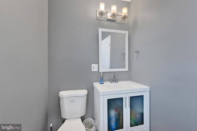 half bath featuring vanity and toilet