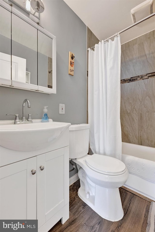 bathroom with toilet, shower / bath combo, wood finished floors, and vanity