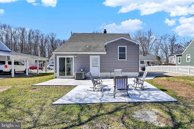 rear view of property with fence, central air condition unit, a chimney, a yard, and a patio