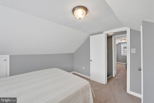 bedroom with light colored carpet, baseboards, and vaulted ceiling